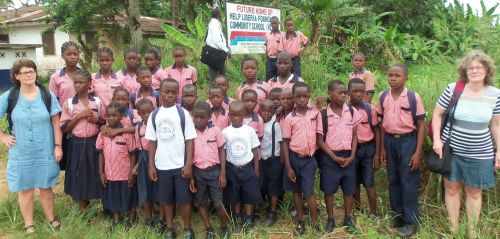 Marianne and Elisabeth posing with students on the school's  future-home site