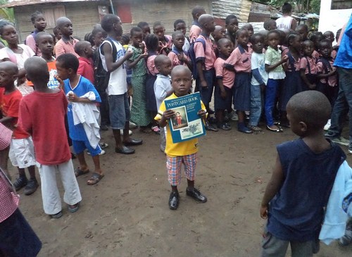 A child displays his book; others wait for theirs