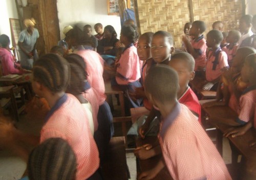 Students standing during the program; in the background are staff members