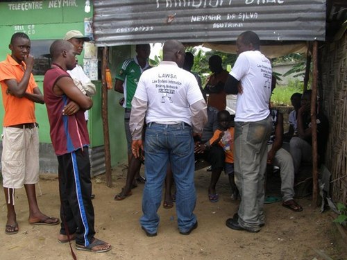 My colleagues talking to a group of people in a makeshift barber shop