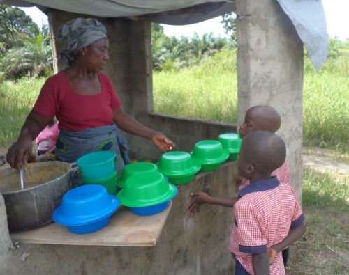 Cook sharing food under the kitchen with tarpaulin roof