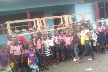 Some kids standing in front of the desks
